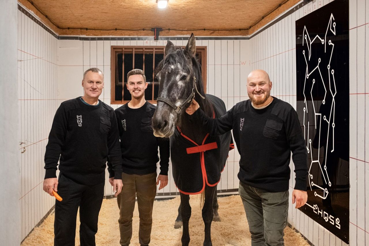 Three of the EHOSS team with the company's own horse in the instrumented stall, the measuring grid printed across the walls behind them