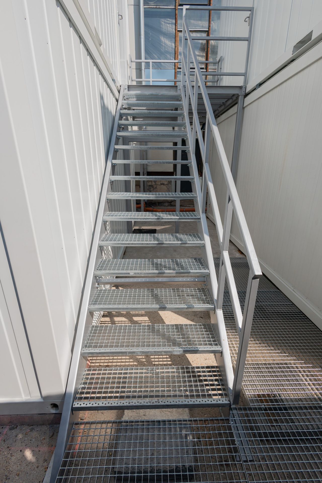 A galvanised steel staircase with a grating landing, installed on site